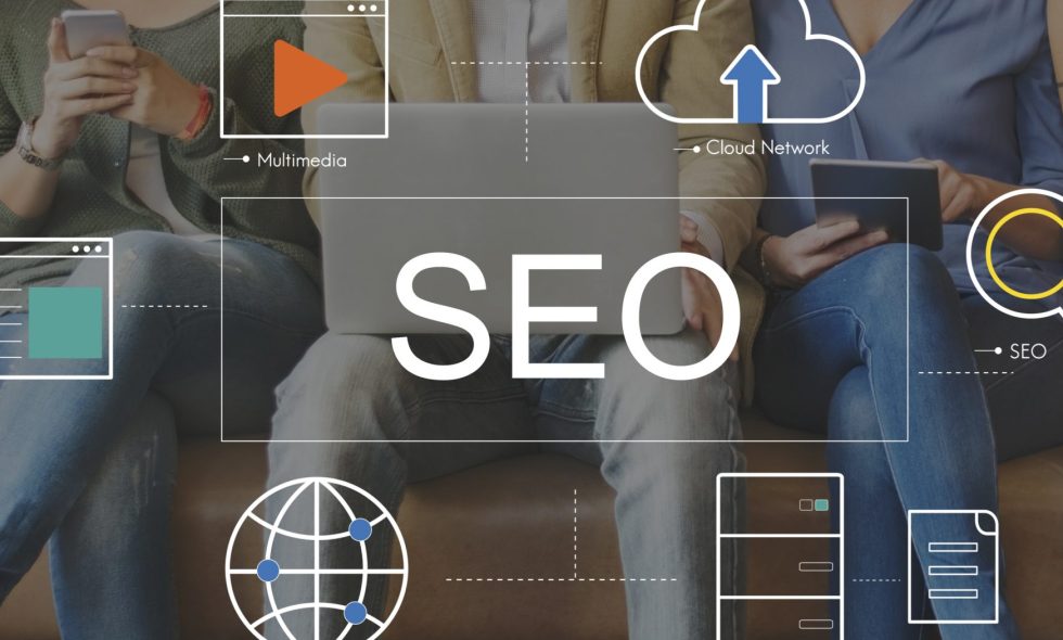Small business owners sitting, surrounded by digital icons representing SEO concepts like keywords, website traffic, and a magnifying glass, symbolizing online visibility and search engine optimization.