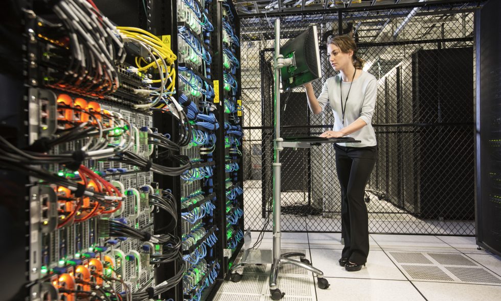 Caucasian woman technician doing diagnostic tests on computer servers in a server farm.
