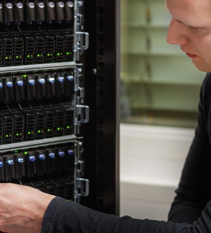 Cloud server manager employee works on datacenter storage device, performing maintenance.